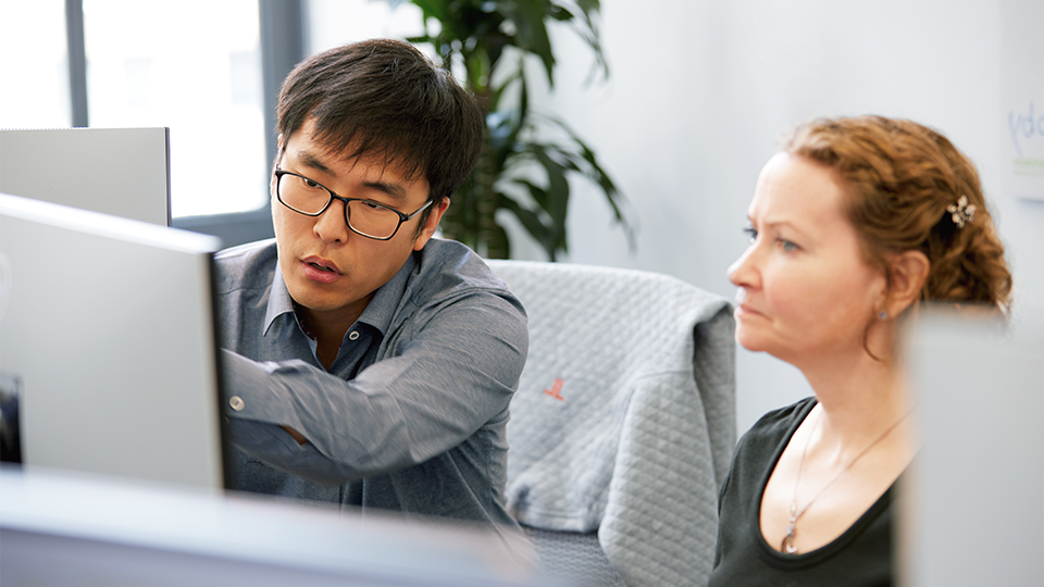 Coworkers examine information on a computer screen.